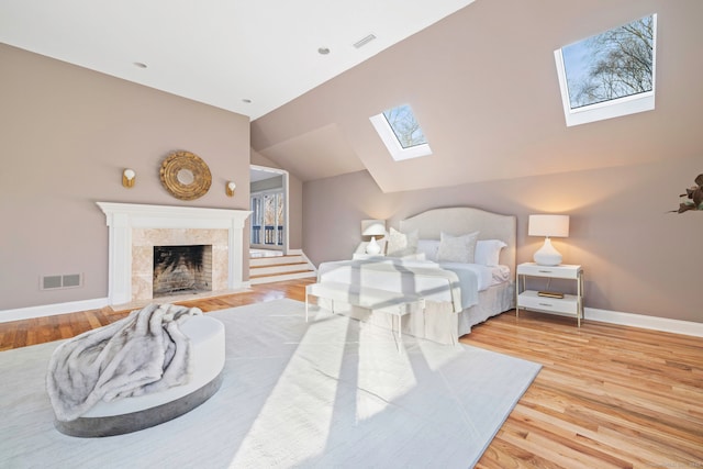 bedroom featuring visible vents, lofted ceiling with skylight, and wood finished floors