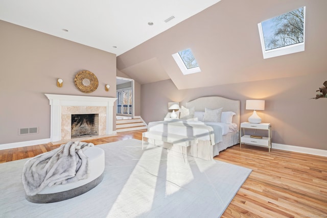 215 Paddock Hill Ln, Fairfield, CT 06824 - bedroom featuring a skylight, wood finished floors, a tiled fireplace, baseboards, and lofted ceiling