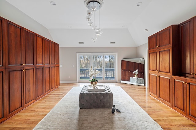 living area featuring visible vents, lofted ceiling, an inviting chandelier, and light wood finished floors