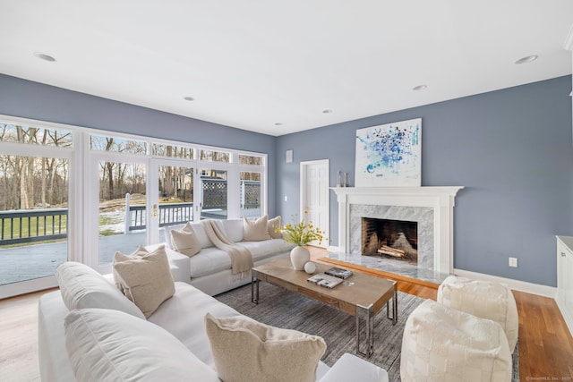 living room with recessed lighting, wood finished floors, baseboards, and a high end fireplace