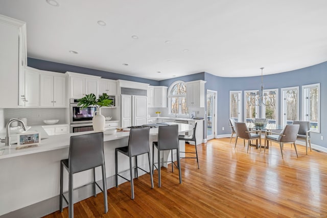 kitchen featuring a sink, light wood-style flooring, white cabinets, and light countertops