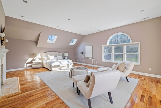 bedroom with visible vents, vaulted ceiling with skylight, light wood-type flooring, and baseboards