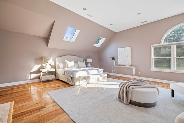 bedroom with baseboards, lofted ceiling with skylight, visible vents, and wood finished floors