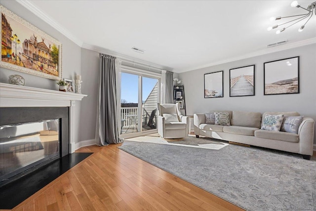 living room featuring a glass covered fireplace, hardwood / wood-style flooring, visible vents, and ornamental molding