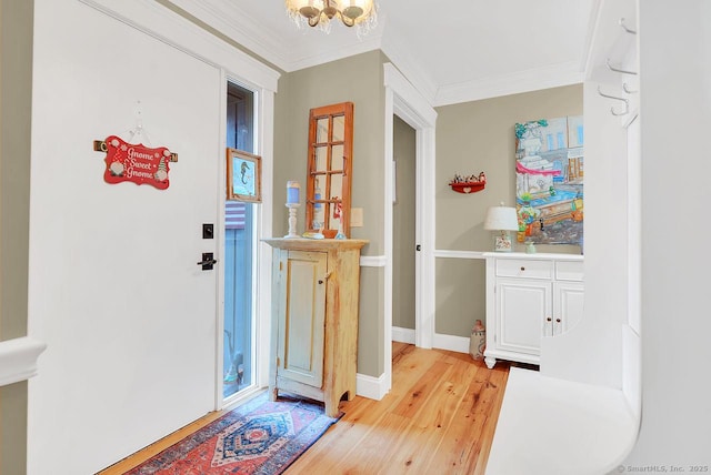 entrance foyer featuring a chandelier, baseboards, ornamental molding, and light wood finished floors