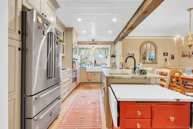 kitchen with light wood finished floors, crown molding, light countertops, freestanding refrigerator, and a kitchen island with sink