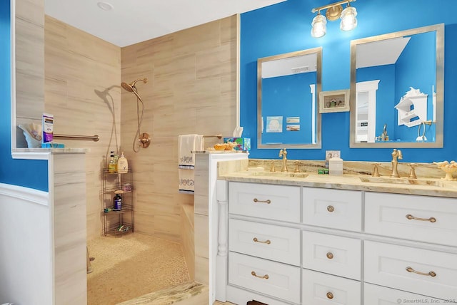 full bathroom featuring a tile shower, double vanity, and a sink