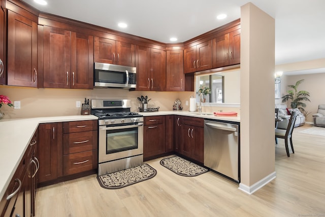 kitchen with a sink, stainless steel appliances, light wood-style flooring, and light countertops