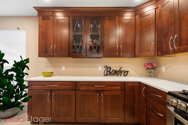 kitchen with stainless steel gas range oven, glass insert cabinets, and light countertops