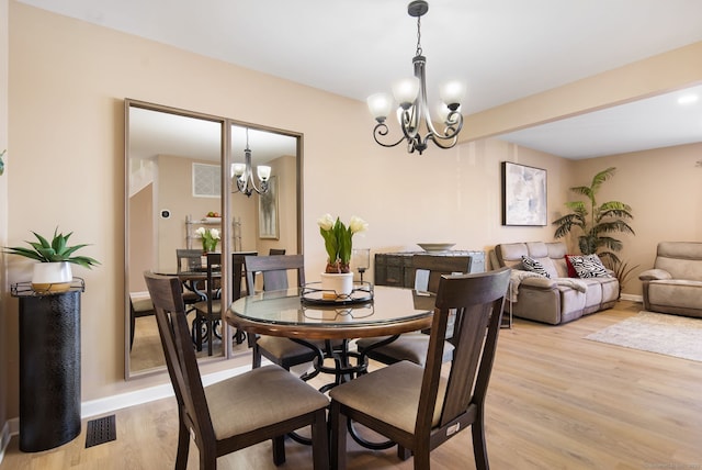 dining area featuring visible vents, baseboards, an inviting chandelier, and light wood-style flooring