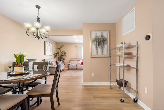 dining room with baseboards, an inviting chandelier, and light wood finished floors