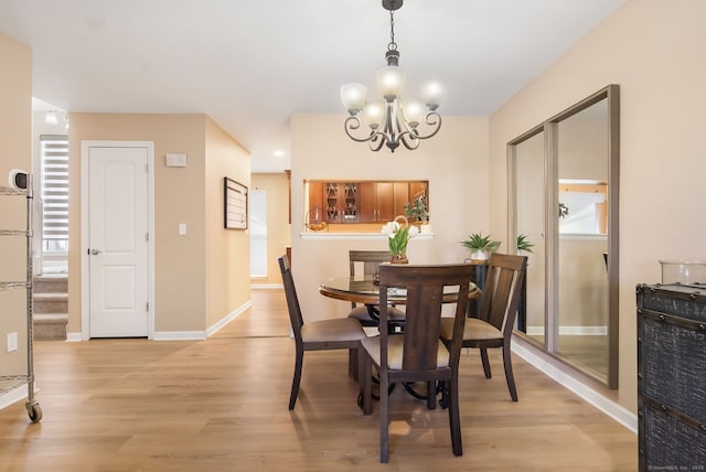 dining room with baseboards, light wood-style floors, and an inviting chandelier