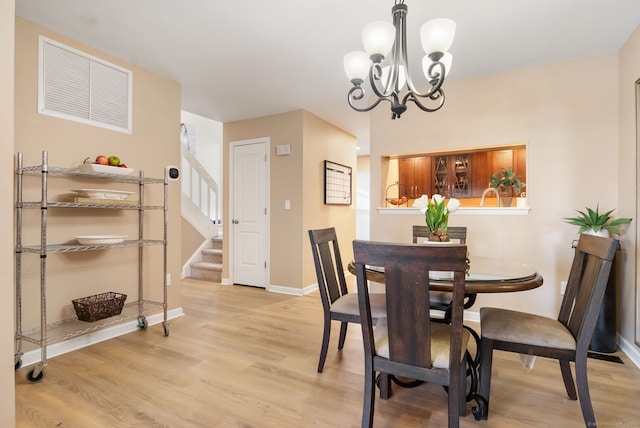 dining room featuring a chandelier, baseboards, stairs, and light wood-style floors