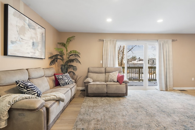 living area with recessed lighting, visible vents, baseboards, and light wood finished floors