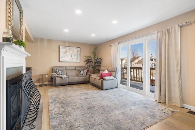 living area with recessed lighting, baseboards, wood finished floors, and a fireplace