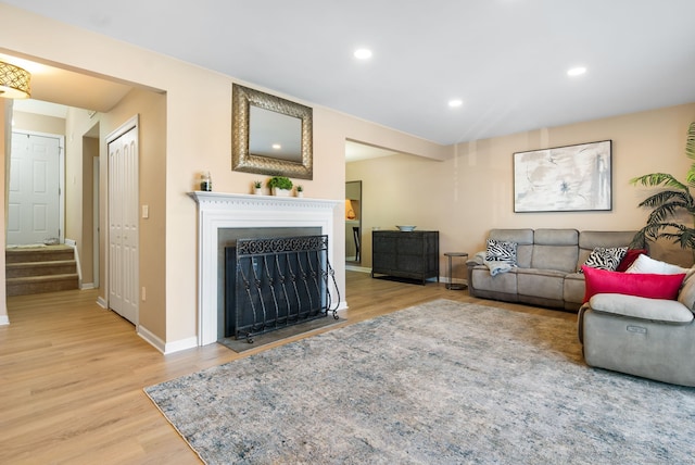 living room with stairway, a fireplace with flush hearth, wood finished floors, and recessed lighting