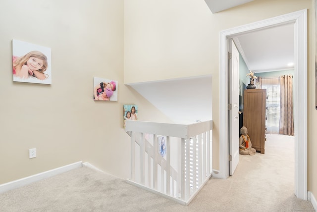 corridor featuring baseboards, an upstairs landing, and carpet