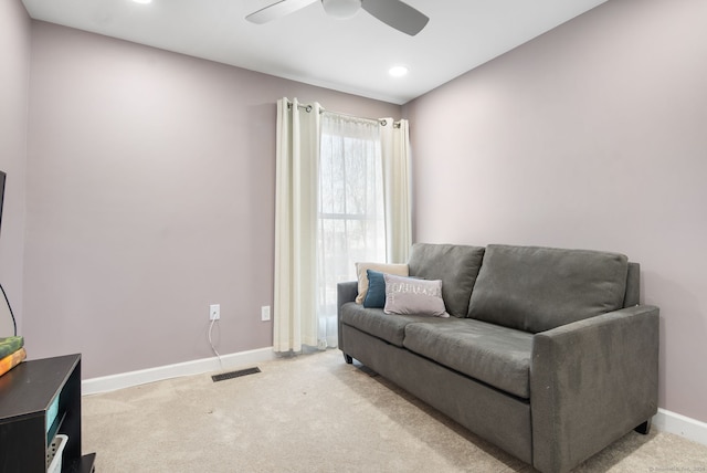 living area with light carpet, visible vents, ceiling fan, and baseboards