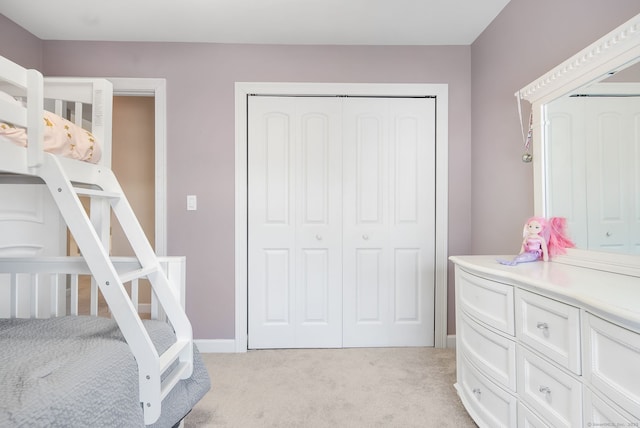 bedroom with light colored carpet, a closet, and baseboards