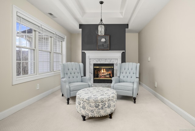 sitting room featuring visible vents, a tray ceiling, carpet floors, a fireplace, and baseboards