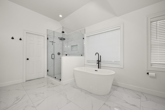 bathroom featuring a soaking tub, marble finish floor, baseboards, and lofted ceiling