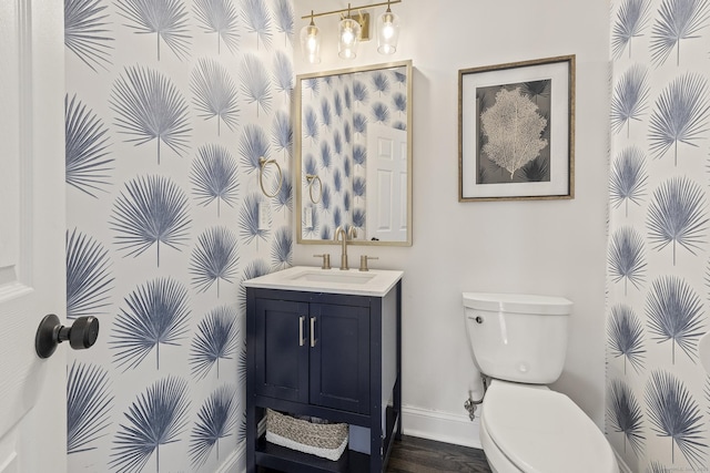 half bathroom featuring baseboards, toilet, wood finished floors, and vanity