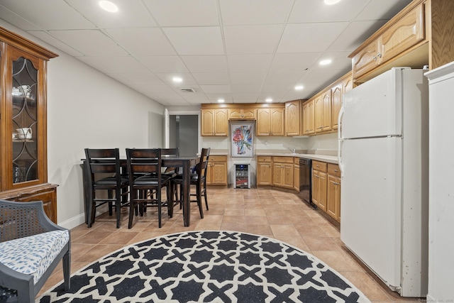 kitchen featuring light tile patterned floors, freestanding refrigerator, light countertops, black dishwasher, and a paneled ceiling