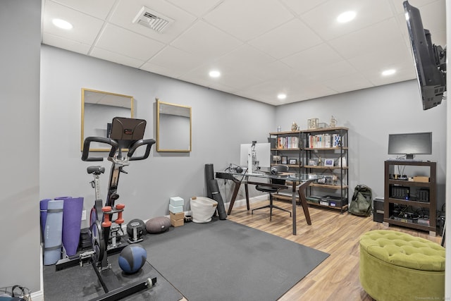 exercise area featuring visible vents, a drop ceiling, baseboards, and wood finished floors