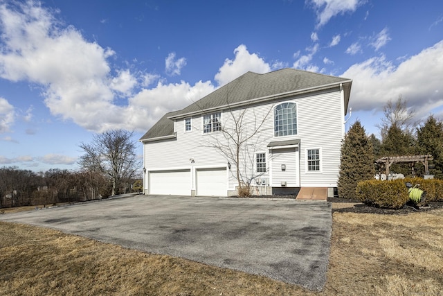 view of front of home with aphalt driveway, roof with shingles, an attached garage, and a pergola