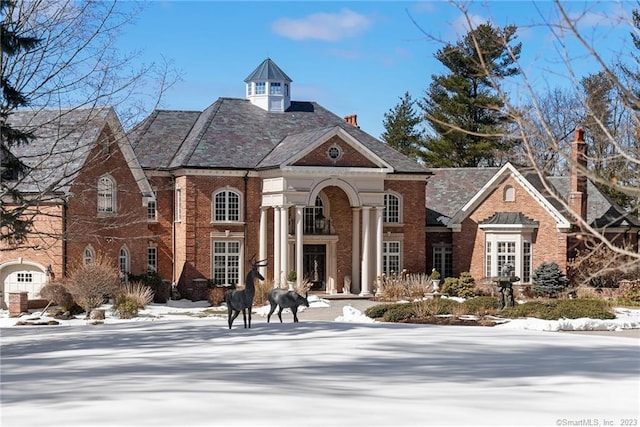 view of front of home featuring brick siding and a chimney