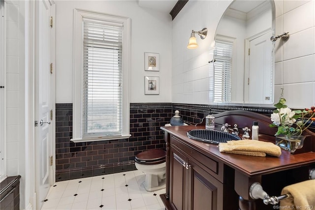 bathroom with vanity, crown molding, tile walls, toilet, and tile patterned floors