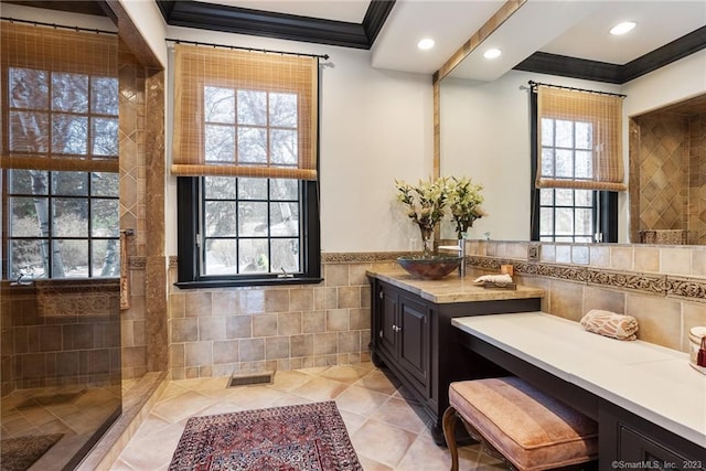 full bath featuring visible vents, ornamental molding, a tile shower, tile walls, and vanity