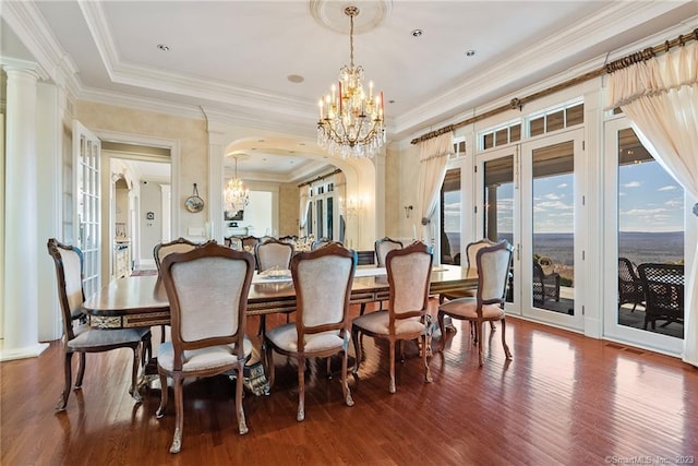 dining area with ornamental molding, an inviting chandelier, wood finished floors, arched walkways, and ornate columns