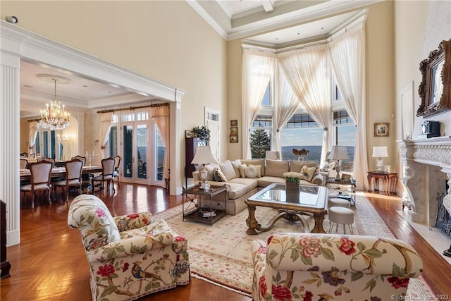 living room featuring a high end fireplace, a chandelier, a towering ceiling, and ornamental molding