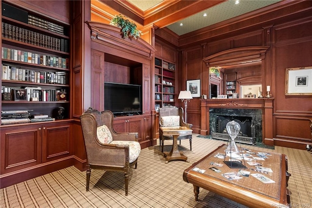 living area with built in features, a high end fireplace, light carpet, crown molding, and a decorative wall