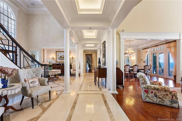 foyer with an inviting chandelier, crown molding, and ornate columns