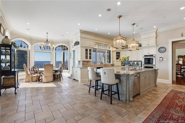 kitchen featuring light stone countertops, a large island, glass insert cabinets, tasteful backsplash, and a chandelier