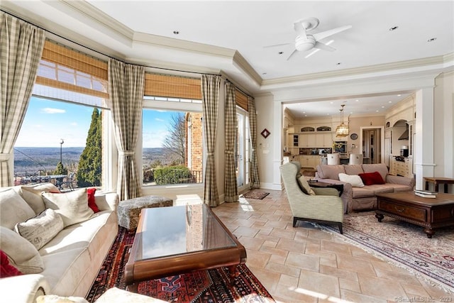 living area with stone tile flooring, a raised ceiling, and crown molding