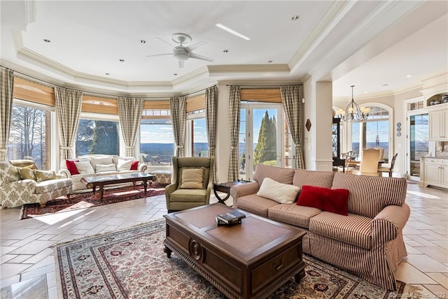 living room with a tray ceiling, stone tile floors, and a healthy amount of sunlight