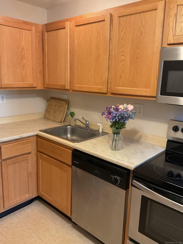 kitchen featuring a sink, stainless steel appliances, light brown cabinetry, and light countertops