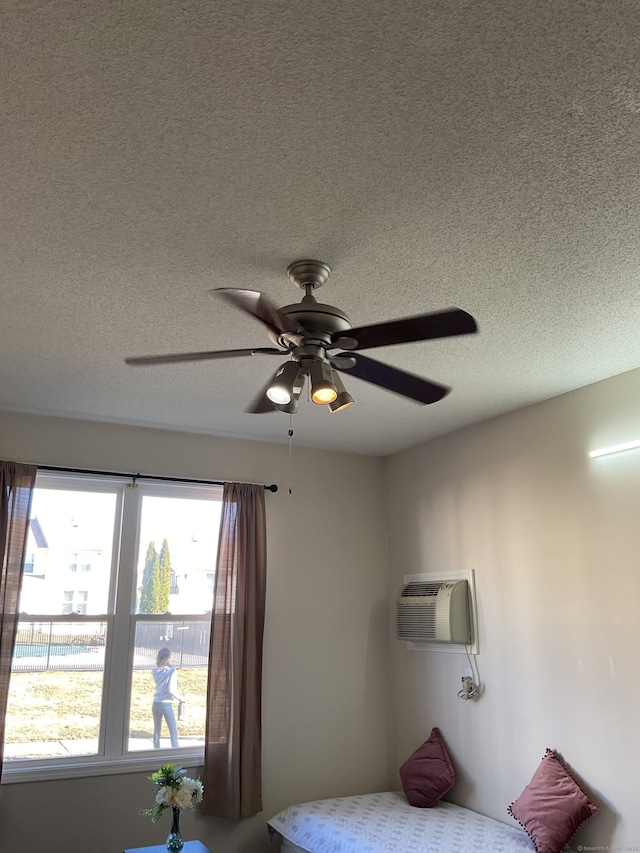 bedroom with a wall mounted air conditioner, a textured ceiling, and ceiling fan