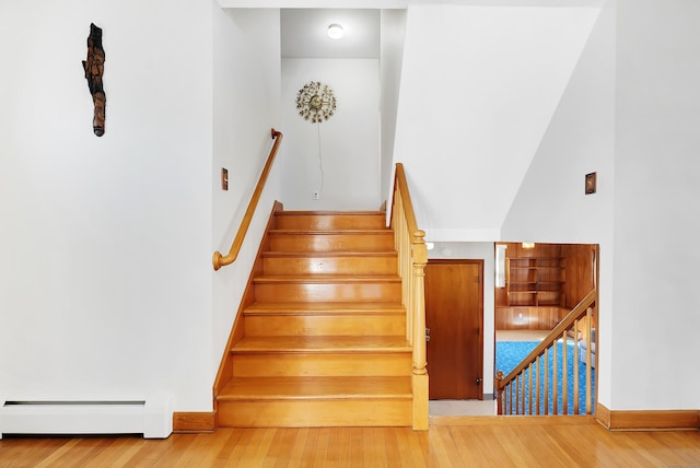 stairs with wood-type flooring, baseboards, and baseboard heating