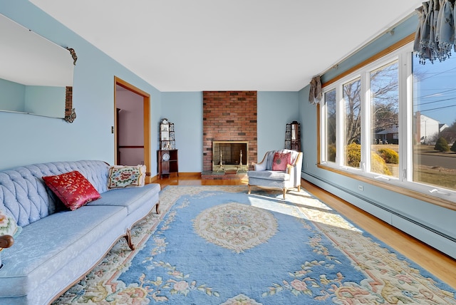 living area with a baseboard heating unit, a brick fireplace, and wood finished floors