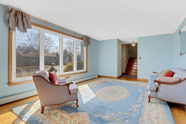 sitting room featuring stairway, baseboards, baseboard heating, and wood finished floors