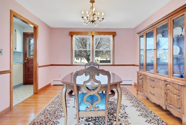 dining room with a baseboard radiator, a notable chandelier, a healthy amount of sunlight, and light wood-style flooring