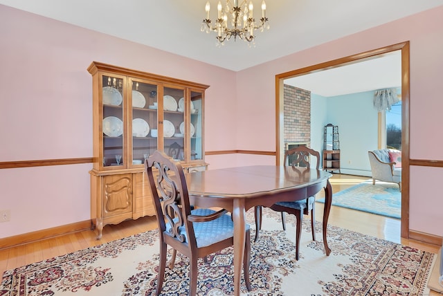 dining room with a chandelier, light wood-style flooring, a fireplace, and baseboards