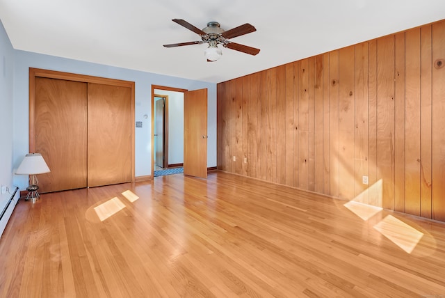 unfurnished bedroom featuring a closet, wooden walls, a ceiling fan, and wood finished floors