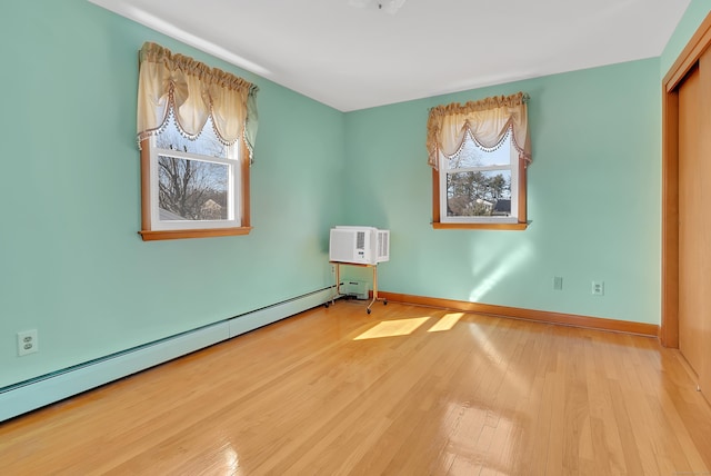 spare room featuring a wall unit AC, baseboards, wood-type flooring, and a baseboard radiator