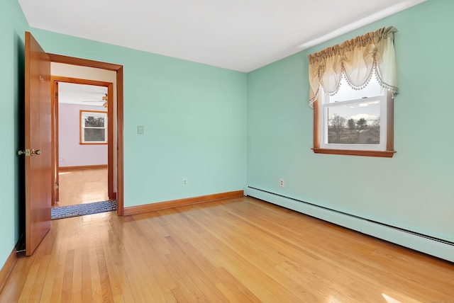 unfurnished room featuring plenty of natural light, baseboards, light wood finished floors, and a baseboard radiator