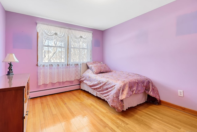 bedroom with light wood-style flooring, baseboards, and baseboard heating